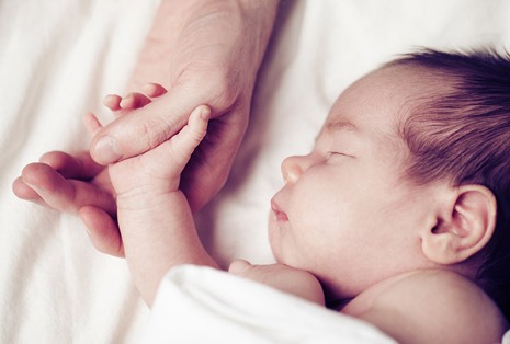 Newborn baby and his father's hand - care and safety concept